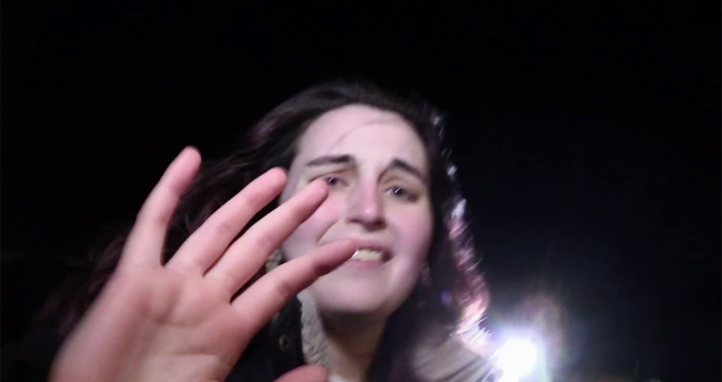 Close-up of a distressed person reaching toward the camera at night.