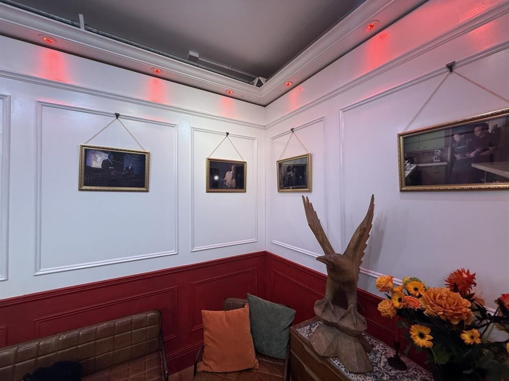 Decorated room corner with framed photographs, red wall panels, and soft lighting