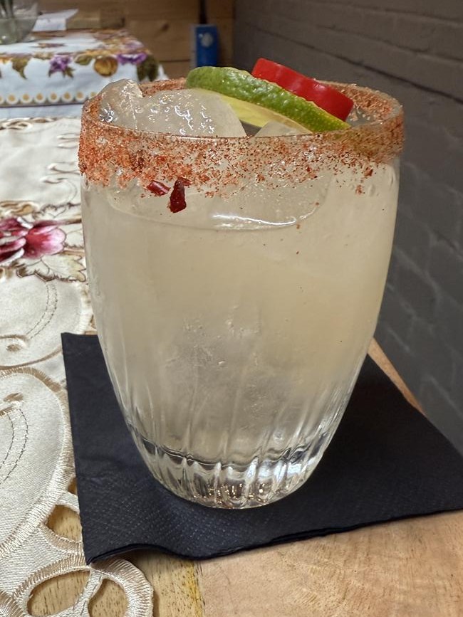 Devil's Breath Cocktail in a glass with a chilli-salt rim, ice, and citrus garnish.